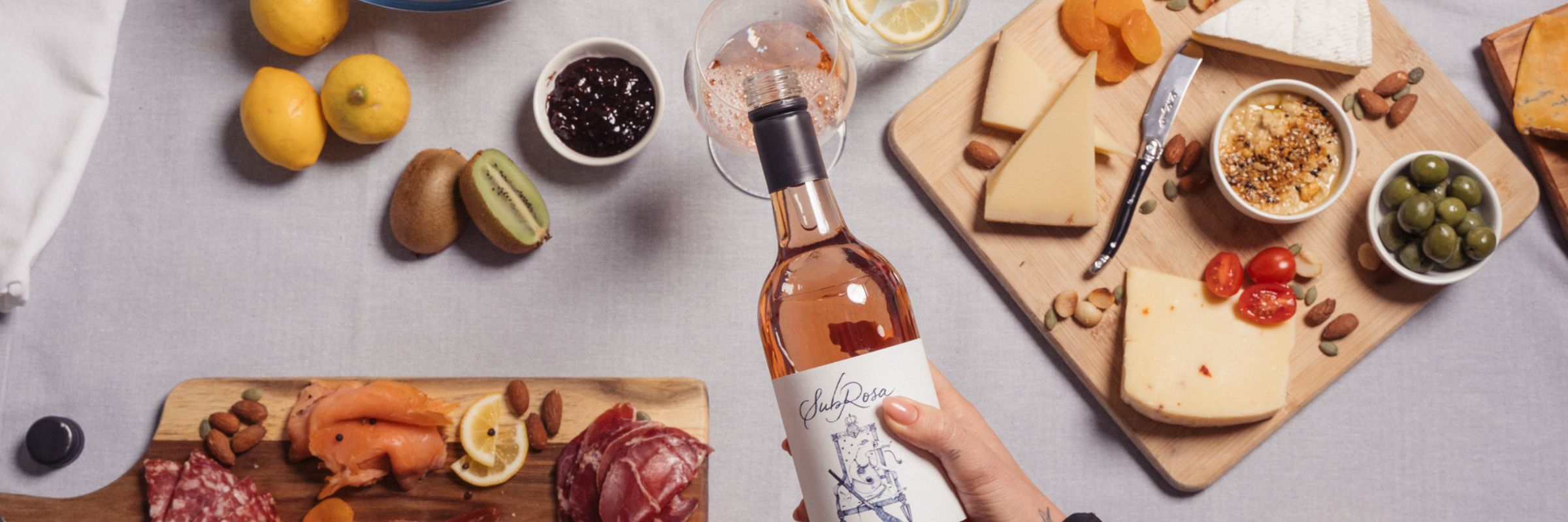 subrosa rose wine being poured into a glass with a charcuterie board in the background