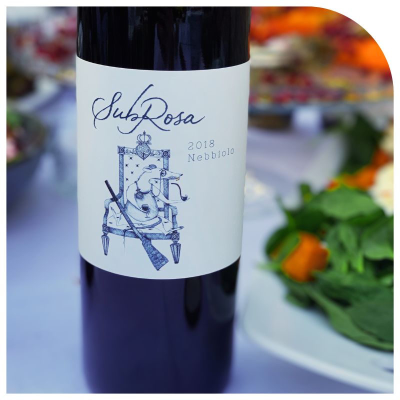 Bottle of SubRosa nebbiolo on a table of food.