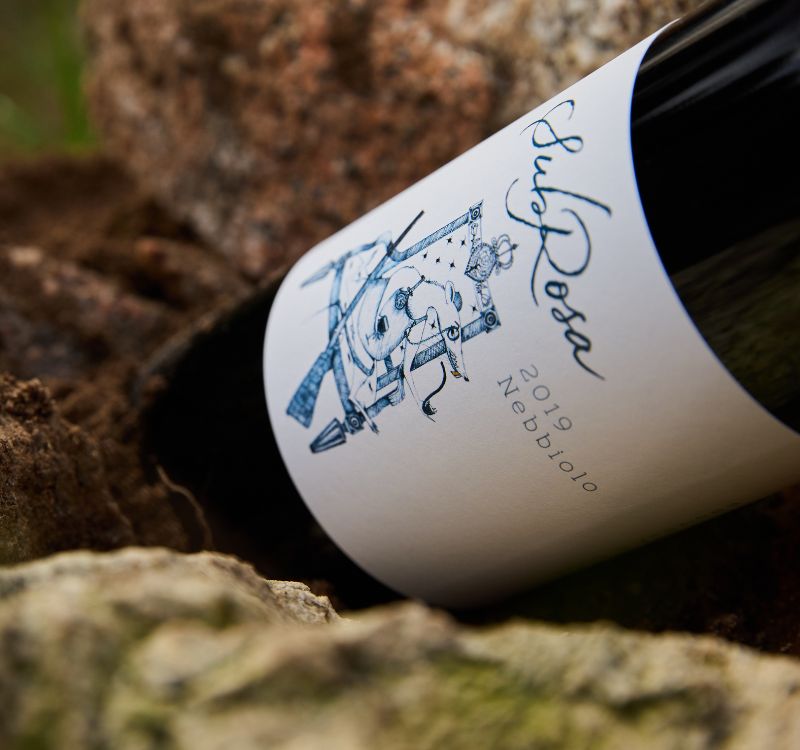 Bottle of 2019 SubRosa nebbiolo pyrenees wine laying in the rocks on the farm in the Grampians.