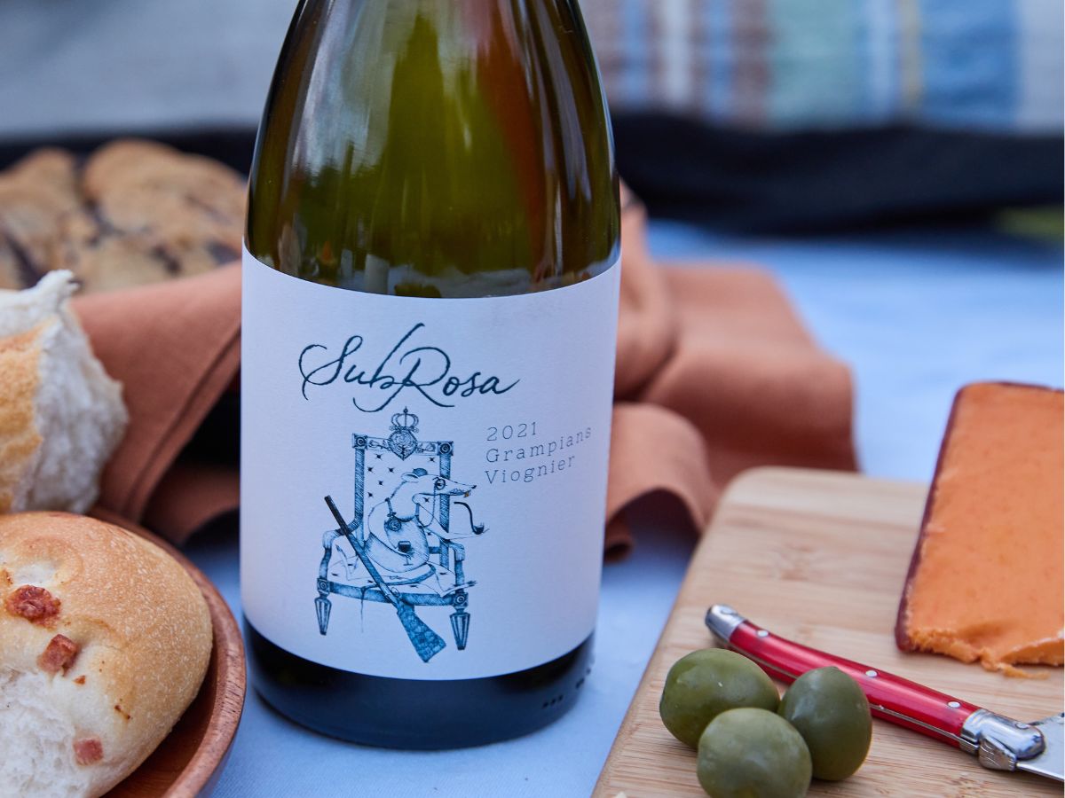 bottle of subrosa grampians viognier on the table with pairing ideas like cheese and olives around it