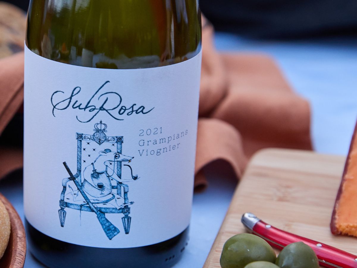 bottle of subrosa viognier opened and on the table surrounded with pairing ideas like olives and cheese