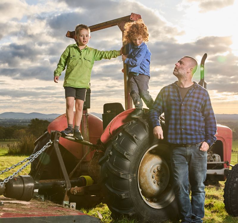 adam louder and his two kids on a red tractor on their subrosa farm in the grampians