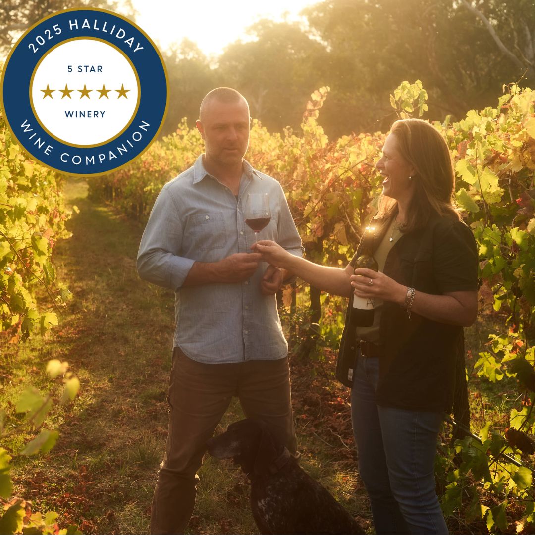 adam louder and nancy panter, owners of subrosa wine in the vineyard with a glass of subrosa shiraz in hand